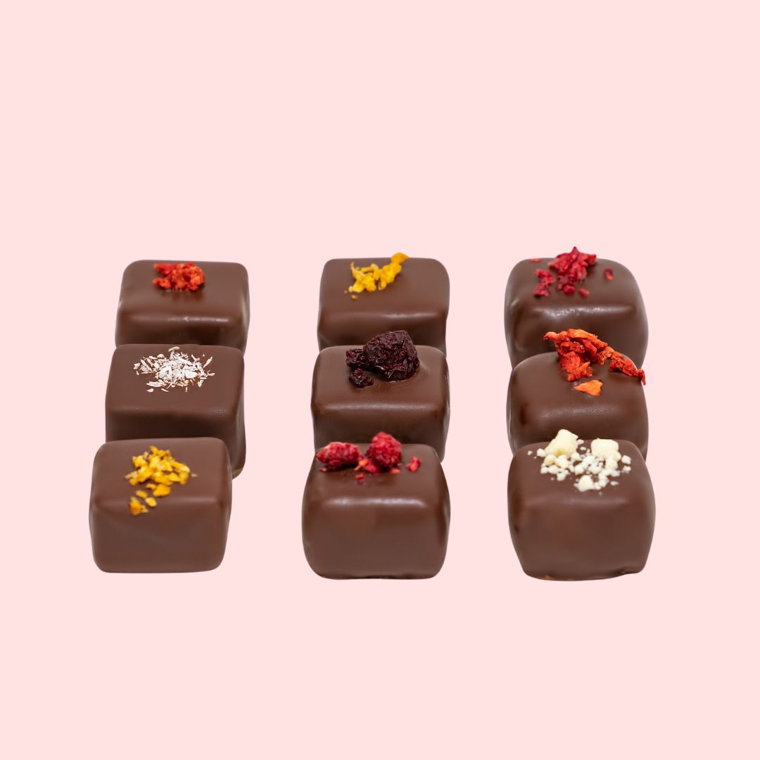 A box of chocolate chocolate with fruity designs, presented in a beautifully decorated pink box.